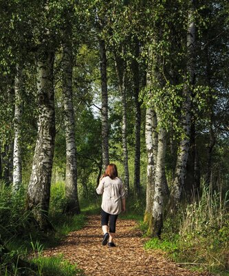 Frau geht auf einem Waldweg spazieren