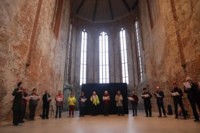 Menschen stehen im Halbkreis in einer Kirche, singend