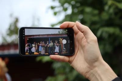 In einer Hand wird ein Mobiltelefon mit einem Foto auf dem Display gehalten.