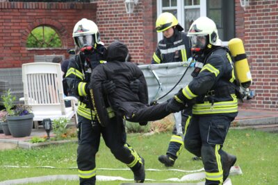 Ein Trupp unter Atemschutz rettet eine Person (hier einen Dummy) nach draußen.