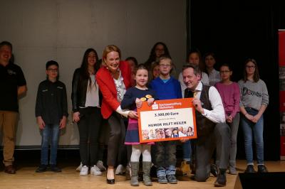 Lars und Paula &uuml;berreichen mit Andrea Helm den Scheck &uuml;ber 3300 Euro f&uuml;r die Stiftung "Humor hilft heilen" an Eckart von Hirschhausen 