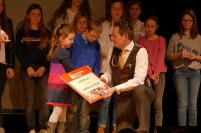 Eckart von Hirschhausen und einige Kinder gucken sich die Spendenurkunde an. 