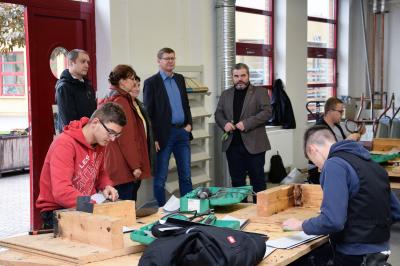 Durften den Auszubildenden gemeinsam mit Lehrbauhofleiter Nino Knobloch (r.) bei ihrer Arbeit &uuml;ber die Schulter schauen: Landrat Siegurd Heinze (2.v.r.), Wirtschaftsf&ouml;rderin der Stadt Gro&szlig;r&auml;schen Cornelia Wobar (2.v.l.), B&auml;rbel Weihmann (3.v.l.) und B&uuml;roleiter Stephan Hornak (l.) vom Landkreis. Foto: Michel Havasi, Handwerkskammer Cottbus  (Bild vergr&ouml;&szlig;ern)