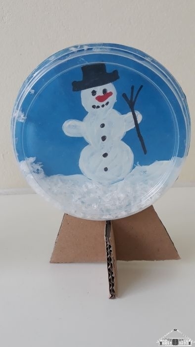 Eine Sch&uuml;ttel-Schneekugel aus einem Jogurtdeckel  (Bild vergr&ouml;&szlig;ern)