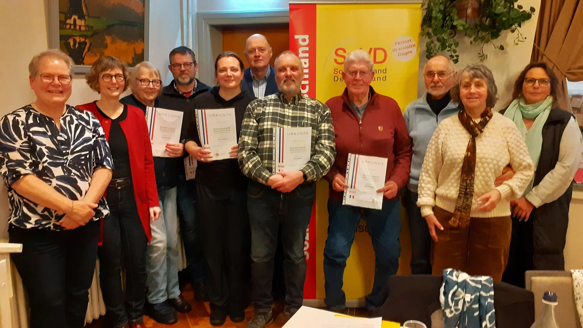 Bild: 27.02.26 - Eine sehr harmonische Jahreshauptversammlung erlebten 93 Mitglieder im „Landgasthof Fegetasch“. Nach dem obligatorischen Rouladenessen wurden die Regularien zügig abgewickelt, zumal man alle bisherigen 12 Vorstandsmitglieder und 4 Revisoren einstimmig für weitere zwei Jahre in ihren Ämtern bestätigte. Darunter auch die Vorsitzende Anne Petersen (Foto li.) und ihre Stellvertreterin Maren Christiansen (Foto 2. von li.). Weiter gab es zahlreiche Ehrungen für langjährige Mitgliedschaften, dabei auch Julius Petersen (Foto 6. v. li.) für 35 Jahre. Nordfrieslands Kreisvorsitzende Petra Lenius-Hemstedt (re.) gratulierte den Geehrten. Maren Christiansen berichtet von einem unserer neu eingetretenen Mitglieder, wo der SoVD sehr unterstützend tätig werden konnte. Nachdem die Krankenkasse zunächst die Kostenübernahme der Leihgebühr für einen elektrischen Rollstuhl abgelehnt hatte und auch der Widerspruch erfolglos blieb, wurde der SoVD eingeschaltet. Mit Erfolg, denn schließlich genehmigte die Krankenkasse die jährliche Kostenübernahme von gut 1.700 Euro. Wieder ein sehr positives Beispiel dafür, wie wichtig der SoVD den Alltag von seinen Mitgliedern verbessern kann.