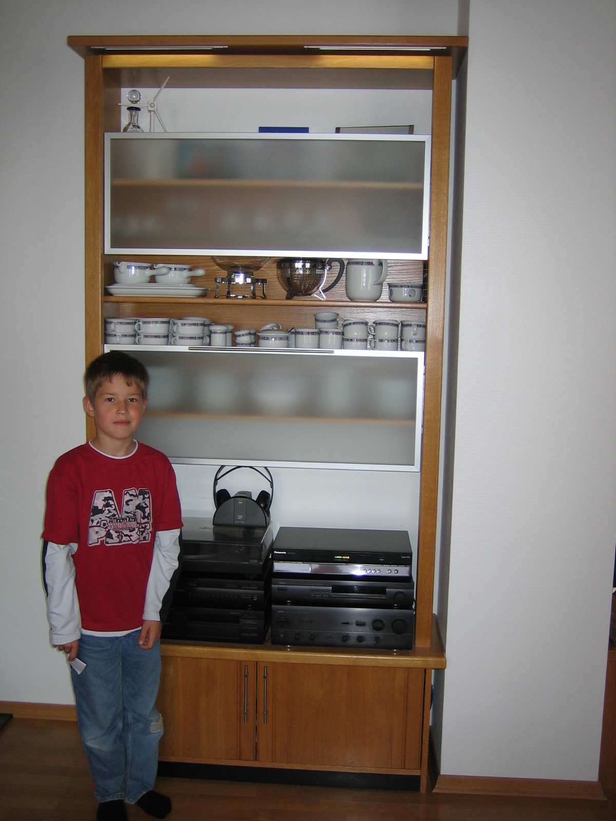 Wandschrank mit Regal mit ge&ouml;ffneten Glast&uuml;ren und einem Jungen  (Bild vergr&ouml;&szlig;ern)