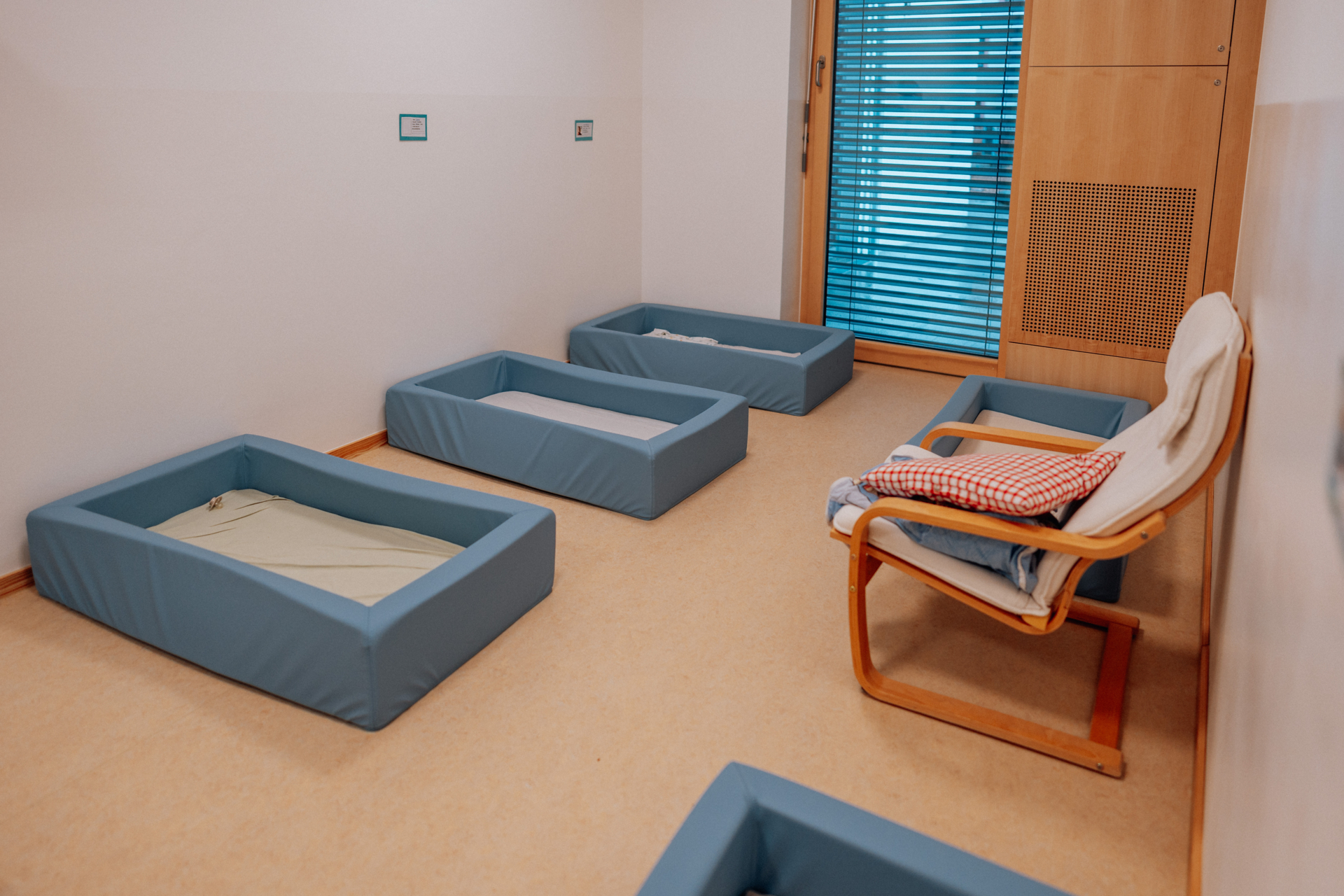 Im Schlafraum hat jedes Kind sein eigenes kleines Nest. Jeder bringt von zuhause mit, womit er sich wohl f&uuml;hlt. Schlafsack, Kuscheltier, Schnuller, Kissen etc. Die Kinder werden selbstverst&auml;ndlich von mindestens einer Fachkraft beim Einschlafen begleitet. Leise Entspannungsmusik und ein Sternenprojektor zaubern eine gem&uuml;tliche und sichere Wohlf&uuml;hl-Atmosph&auml;re.  (Bild vergr&ouml;&szlig;ern)