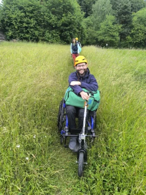 Vorschaubild: Teilnehmer mit Rollstuhl auf einem Feldweg zur Kletterwand