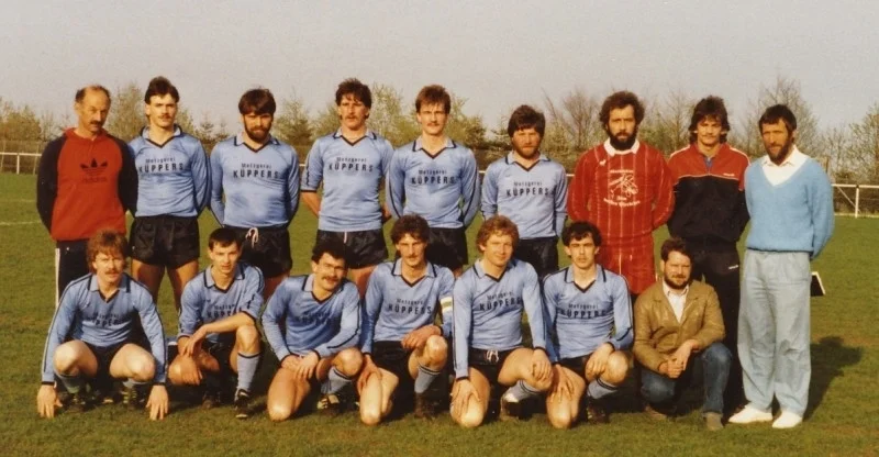 1. Mannschaft 1987 Hinten v.l.: Trainer Helmut V&ouml;ll, Rolf Weishaupt, Karl Volpatti, Reiner F&ouml;rster, Walter Pr&uuml;mmer, Reiner Huppertz, Winnie Breuer, Lothar Sommer und 1. Vors. Hansj&uuml;rgen Nie&szlig;en Vorne v.l.: Georg Sommer, G&uuml;nter Bauer (Bruder von Winnie), Edgar Schreiber, Stefan Jentges, Stefan Carl, Gerd Steffens und 2. Vors. Erwin Sauer  (Bild vergr&ouml;&szlig;ern)