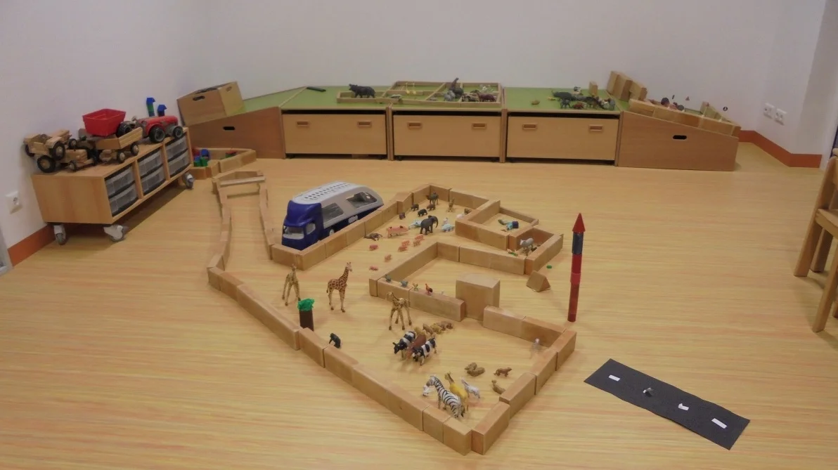 Bild: Der Bauraum(Wandelraum) bietet den Kindern verschiedenartige Bausteine an und ist mit viel Platz ideal geeignet das Bauen mit dem Rollenspiel zu verbinden. Material lockt zum Ausprobieren und die Gewissheit, dass die Bauwerke stehenbleiben und abends gezeigt werden können, ist für das Selbstwertgefühl unserer kleinen Baumeister enorm wichtig. Dieser Raum wird flexibel an die Spielbedürfnisse der Kinder angepasst und umgestaltet.