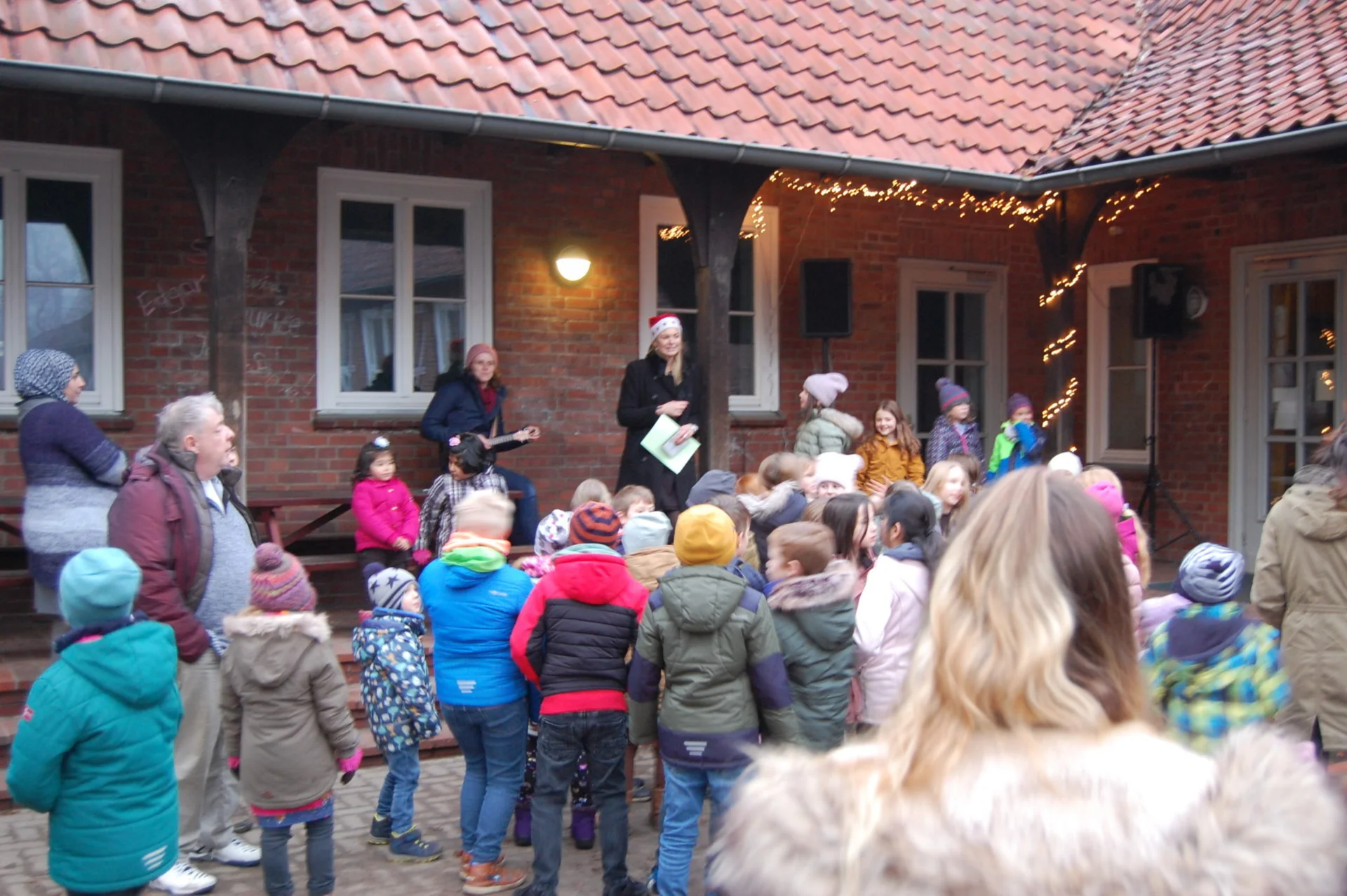 Frau Lindner begr&uuml;&szlig;t alle G&auml;ste, die sich um 16.00 Uhr auf dem Schulhof versammelt haben.  (Bild vergr&ouml;&szlig;ern)