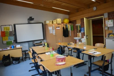 Vorschaubild: Das ist ein Klassenraum im Neubau. Die Klassenräume haben einen Arbeitsraum und einen Nebenraum. Die Klassen haben ein Whiteboard, ein Computer und genug Platz zum Arbeiten.