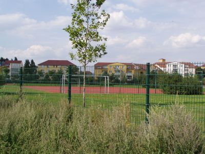 Der Sportplatz der Grundschule bietet zwei Gummihartplätze mit Zäunen hinter den Toren.