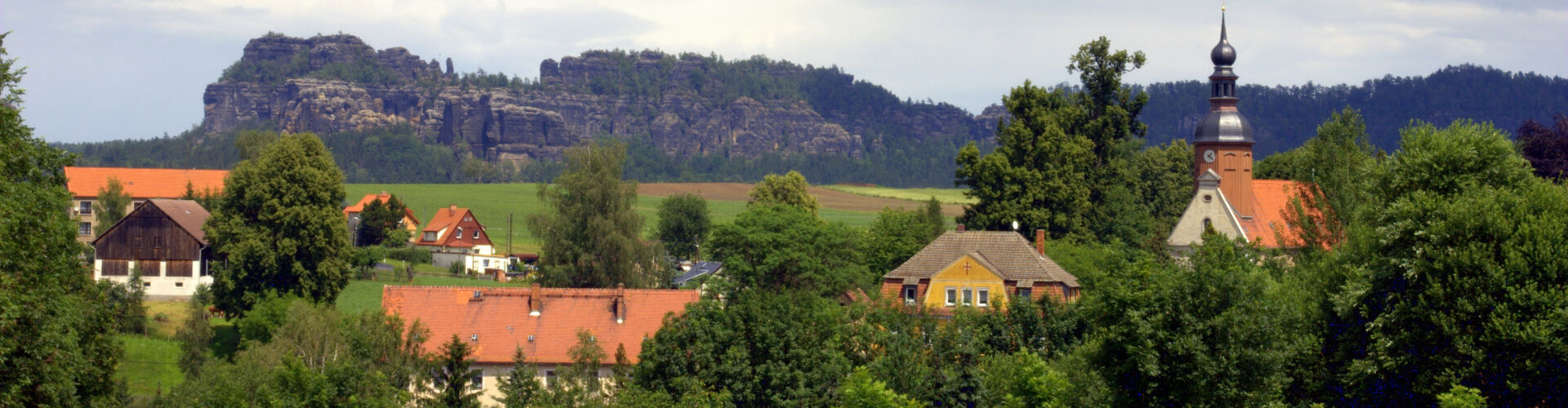 Blick von Reinhardtsdorf mit Kirche zu den Schrammsteinen