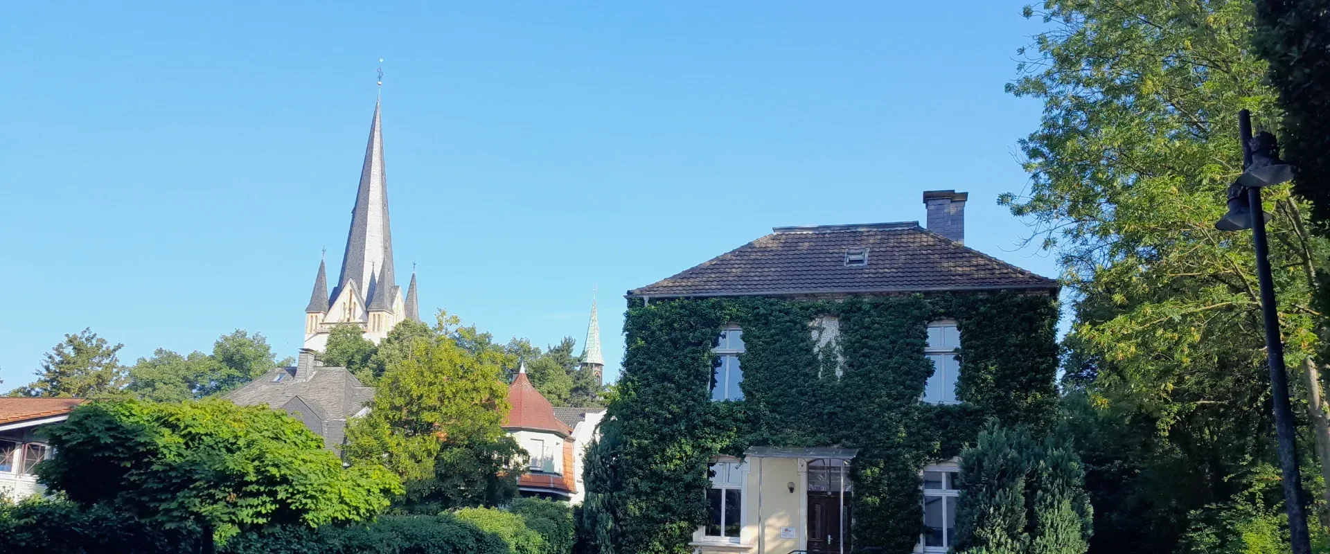 Foto: Stadtbild mit dem Gebäude vom SKFM Menden e.V. und dem Kirchturm der St. Vincenz Kirche