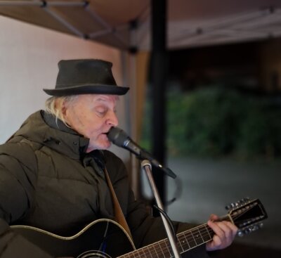 Burkhard Goers sang und spielte Weihnachtslieder vor dem Tintenfass, dem Vereinshaus in der Magdeburger Straße. (Bild vergrößern)