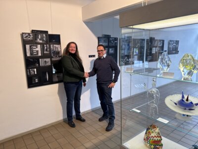 Museumsleiterin Ellen Kabelitz wird von Bürgermeister Lars Obermann im Glasmuseum begrüßt vor der noch bis zum 31.01.2025 aktiven Ausstellung „Lilli Jahn - Wir bleiben unlöslich miteinander verbunden.“ (Bild vergrößern)