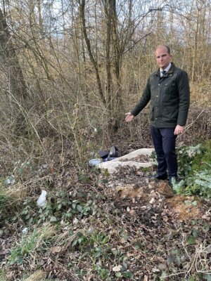 Kreisbeigeordneter Dr. Philipp Kanzow weist auf illegal an einem Wanderparkplatz entsorgten Abfall unter anderem Altöl, Grünschnitt und einen Teppich hin. (Bild vergrößern)