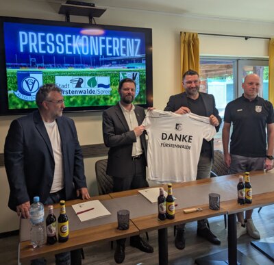 Sportdirektor Torsten Matuschke (2. vr) übergibt Bürgermeister Matthias Rudolph (2. vl) nach der Unterzeichnung des Nutzungsvertrages als Dank ein Sondertrikot aus Altglienicke.. (Bild vergrößern)
