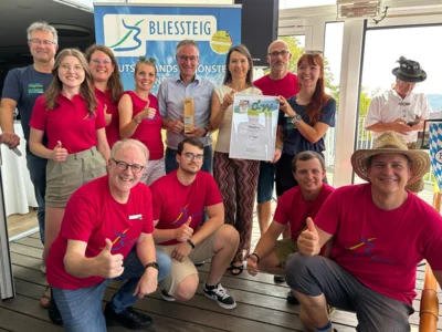 Hintere Reihe, von links: Moderator Manuel Andrack – Wandermagazin, Julia Serov – Saarpfalz-Touristik, Nina Burgey-Wack – Saarpfalz-Touristik, Katrin Thieser – stellv. Leiterin Saarpfalz-Touristik, Frank John – Landrat Saarpfalz-Kreis, Yorgova-Ramanauskas – Staatssekretärin, Torsten Czech – Leiter Stabsstelle für Nachhaltige Entwicklung und Mobilität, Marieke Wist – Redakteurin Wandermagazin Vordere Reihe, kniend: Wolfgang Henn – Geschäftsführer Saarpfalz-Touristik, Luckas Boßlet – Wegepate Bliessteig, Maurice Eickhoff – Mobilitätsmanager, Tomas Menges – Wegepate Bliessteig (mit Hut) Foto: Stefan Eins, Gemeinde Mandelbachtal‎
