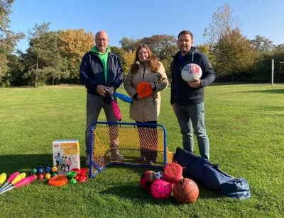 Sportjugend-Mitarbeiterin Ann-Kathrin Husar (m.) und KSB-Geschäftsführer Florian Bortfeldt (r.) überreichen dem Leiter der Jugendherberge Haldensleben Ingolf Zander eine kleine Auswahl an Sport- und Spielgeräten. (Bild vergr&ouml;&szlig;ern)