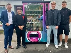 Von links: Erster Bürgermeister Nicolas Lahovnik und Vorsitzender der Jugendvertretung Maged Dawas freuen sich gemeinsam mit den Betreibern Sebastian Dreßel und Joshua Möhwald über den neuen Snackautomaten am Busbahnhof.