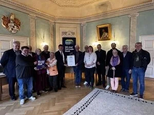 Im Beisein der Steuerungsgruppe, von Vertretern aus Schule und Kirche sowie Mitgliedern des Stadtrats erhält Erster Bürgermeister Nicolas Lahovnik die Fairtrade-Town-Urkunde aus den Händen von Fairtrade-Botschafter Manfred Holz.