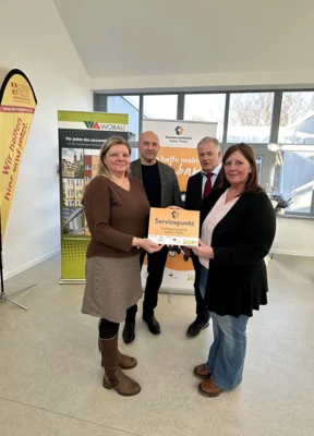 Yvonne Jahn vom PiA e.V. (li.) übergibt Kathrin Roussiére, Leiterin des Servicepunktes im ASB-Treffpunkt „Müntze“, im Beisein von Magdeburgs Sozialbeigeordnetem Dr. Ingo Gottschalk (2.v.l.) und Wobau-Geschäftsführer Peter Lackner das Servicepunkt-Schild. Quelle: ASB RV MD e.V. (Bild vergr&ouml;&szlig;ern)