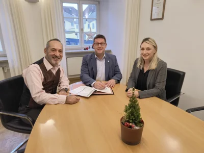 : (v.l.) Betriebsleiter Dominique Barreteau mit Bürgermeister Helmut Fichtner und Standesamtsleitung Silvia Kaindl bei der Unterzeichnung des Vertragswerks zur Übergabe von hoheitlichen Friedhofsaufgaben an das Bestattungsunternehmen Maushammer.  Fotografiert von Christin Grundmann-Fritz für die Stadt Mainburg. (Bild vergr&ouml;&szlig;ern)