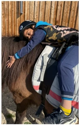 Kind lehnt sich an das Pferd (Bild vergr&ouml;&szlig;ern)