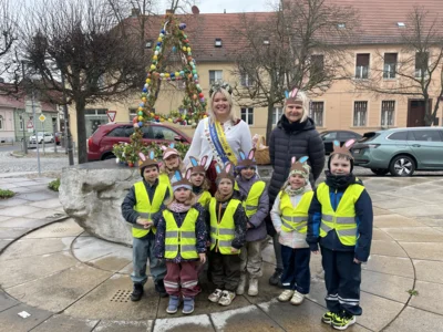Die "Füchse" der Kita-Rhinstrolche mit Erntekönigin Jenny und Frau Gruhn vor dem Osterbrunnen.
