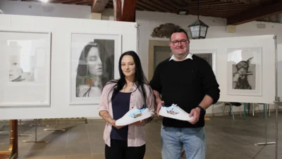 Die Künstlerin Julia Weise und Bürgermeister Andreas Nette mit einem Paar Querfurt-Sneaker. Diese sind, so wie auch weitere Werke der Künstlerin, im Foyer des Rathauses zu bestaunen.