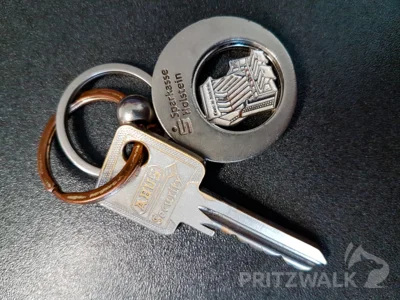 Ein einzelner Schlüssel mit Anhänger und eine rote Geldbörse liegen im Pritzwalker Fundbüro zur Abholung bereit. Foto: Stadt Pritzwalk (Bild vergr&ouml;&szlig;ern)