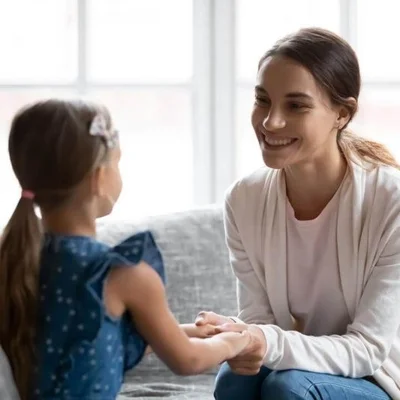 Ein Elternteil spricht ruhig und aufmerksam mit einem Kind – Symbol für Verbindung, emotionale Sicherheit und bewusste Kommunikation im Familienalltag. (Bild vergr&ouml;&szlig;ern)