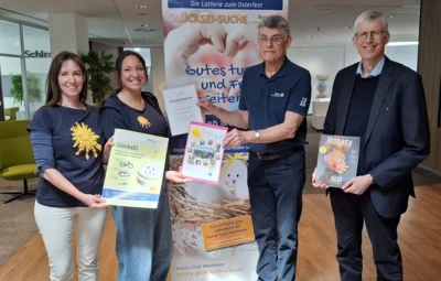Foto: Auf dem Foto sieht man vier Personen. In der Mitte steht ein Roll-Up zum GlücksEi-Projekt. Links neben dem Roll-Up stehen Heike Klemm und Christina Luhn. Rechts neben dem Roll-Up stehen Jürgen Engert und Christian Hock. Alle vier Personen schauen in die Kamera und lächeln. Jede Person hält etwas in den Händen: ein Plakat zum GlücksEi-Projekt, eine Schenk-Urkunde, ein Danke-Plakat sowie ein Heft vom Rotary Club. Das Foto hat Günther Grosch gemacht. Foto zur Meldung: Das GlücksEi-Projekt des Rotary Club Weinheim