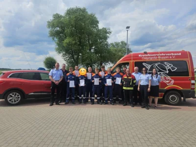 Kinder des Schulfaches Feuerwerhr vor zwei Feuerwehrfahrzeugen (Bild vergr&ouml;&szlig;ern)