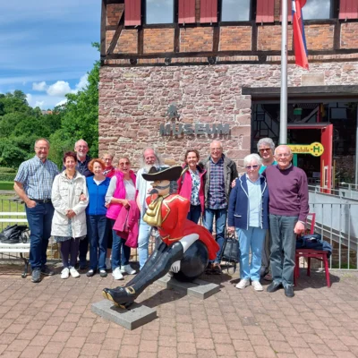 Gruppenfoto vor dem Münchhausen-Museum in Bodenwerder. Die Reisegruppe steht um eine Figur herum, die Baron von Münchhausen auf einer Kanonenkugel reitend darstellt. (Bild vergr&ouml;&szlig;ern)