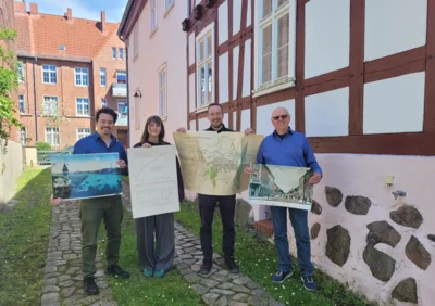 (v. l. n. r.) Lukas Rogner (mit Postkarte vom Hafen), Mia Fee Husack (mit WIKO-Plakat), Marcel Steller (mit Stadtplan von 1913), Burkhard Genth (mit Postkarte der Moltkestraße) vor dem Stadtmuseum. (Foto: Birte Giese/Stadtmuseum) (Bild vergr&ouml;&szlig;ern)