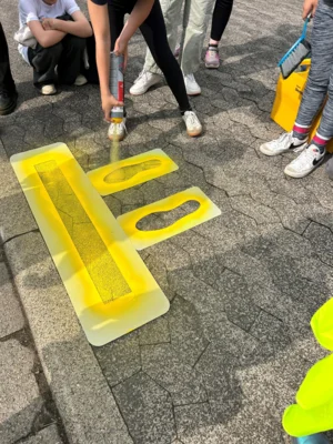 Schülerinnen und Schüler der Klasse 3b sprühen die gelben Füße für mehr Sicherheit auf dem Schulweg. (Bild vergr&ouml;&szlig;ern)