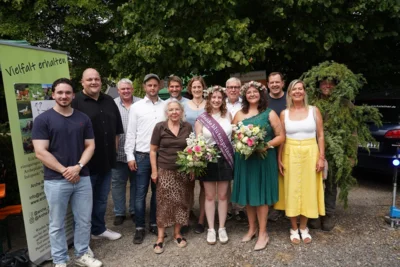v.l.n.r.  hintere Reihe: Lutz Löwer (Stadtverordneter), Manuel Steiner (Bürgermeister Nationalparkstadt Frankenau), Heiko Backhaus (ehem. Ortsvorsteher Altenlotheim), Sascha von Drach (Ortsvorsteher Altenlotheim), Manuel Schweiger (Leiter Nationalpark Kellerwald-Edersee), Kristin Gampfer (Geschäftsführerin Naturpark Kellerwald-Edersee), Jürgen Frömmrich (MdL), Frederik Westmeier (Bürgermeister Nationalparkgemeinde Edertal), Wacholdermännchen (Ranger Torsten Daume)  vordere Reihe: Iris Ruhwedel (stellv. Kreistagsvorsitzende Waldeck-Frankenberg), Jana Heck (amtierende Heideblütenprinzessin), Saija Ludwig (Heideblütenprinzessin bis 2026), Susanne Kubat (Vertreterin für Nationalparkgemeinde Vöhl) BILDQUELLE: Nationalpark Kellerwald-Edersee (Bild vergr&ouml;&szlig;ern)