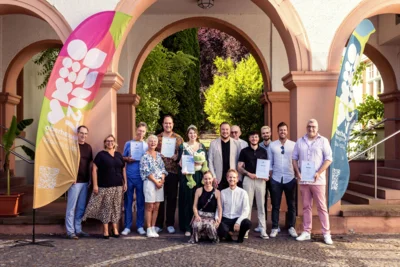 Sind die richtigen Köpfe zusammen, dauert es nicht lange, bis neue Ideen kursieren. Das Team rund um die Landesgartenschaugesellschaft, Familie Bethke vom Herbarium Boutiquehotel Kurhaus mit den neuen Botschaftern. Das sind: Martin Schneider, Boris Meinzer, Tobias Bartel, Froschkönigin Tabea Isabelle I. und die Crew von Afterhour Eierbagge. Foto: LGS/ Verena Holland (Bild vergr&ouml;&szlig;ern)