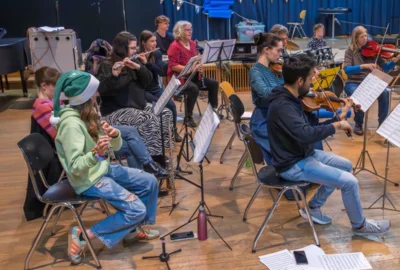 Eine Orchesterprobe mit ROOF und YOUNGSTARS. Eine Flötistin trägt eine grüne Nikolausmütze.