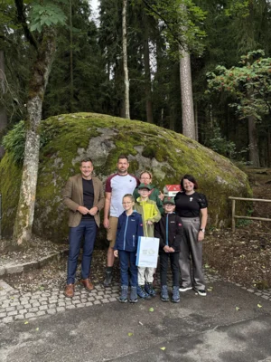 Erster Bürgermeister Nicolas Lahovnik (links) und Eva Theresa Beck, Leiterin des Kultur- und Tourismusmarketings der Stadt Wunsiedel (rechts), begrüßen die Familie Toußaint als 50.000. Besucher im Felsenlabyrinth und überreichen ein kleines Geschenk.