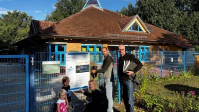 Sanierung der Kita Lindenblüte in Ruhland: Im Beisein von zwei Kitakindern bringen Einrichtungsleiterin Yvonne Förster, Bauleiter Stephan Hain und Architekt Martin Tiede das Bauschild an. - Johannes Martin / Diakonie Libera