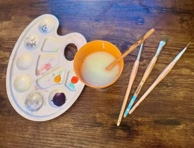 Eine Palette mit Farben, Pinseln und einem Wasserbecher, Bild: Fenja Pioch