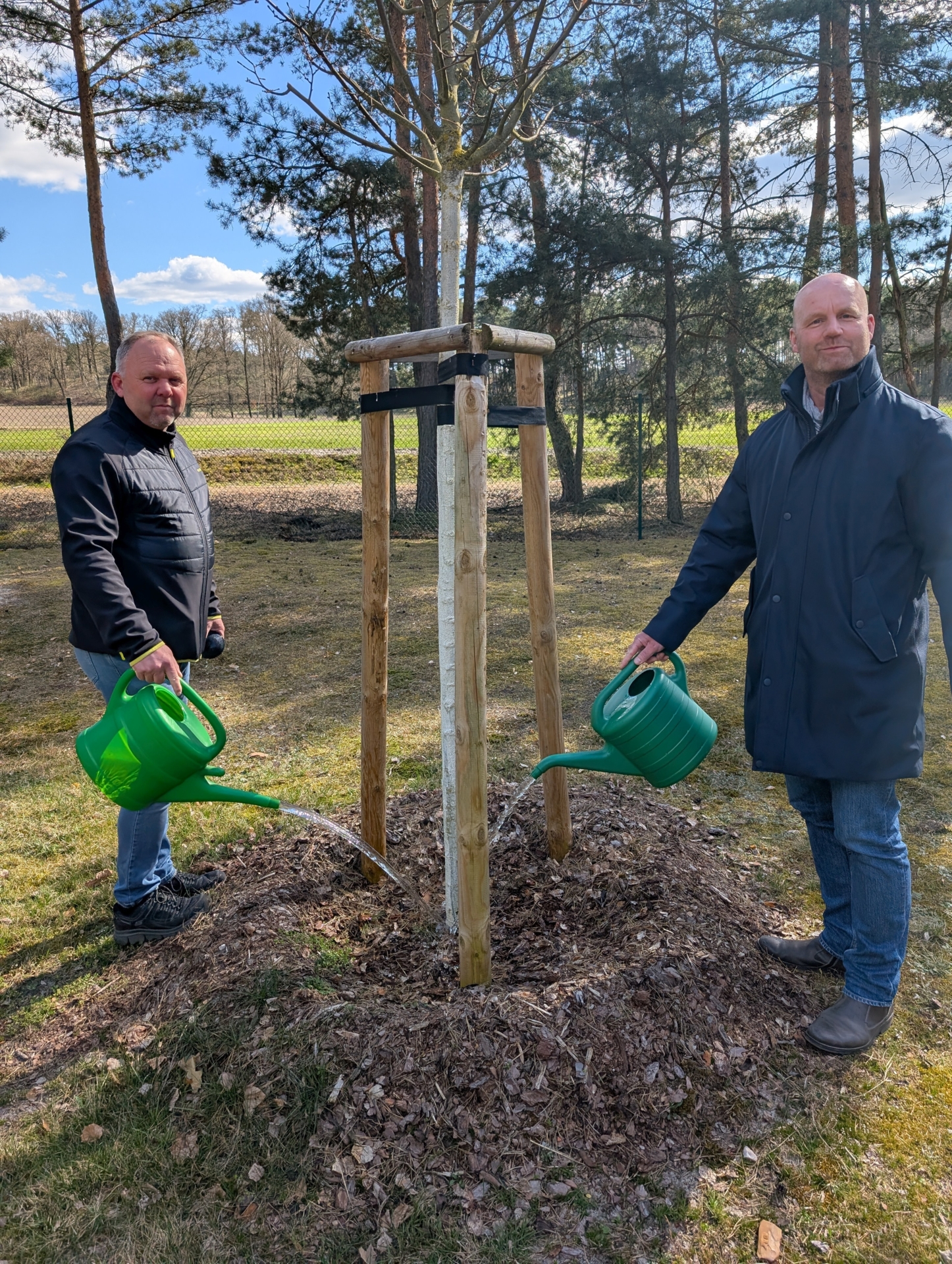 Am Friedhof in Schrakau nutzten Ortsvorsteher Heiko Maaß und Bürgermeister Marco Babenz die Gelegenheit, um einen jungen Baum mit einer kleinen Erfrischung zu versorgen. Foto: Stadt Calau / Jan Hornhauer