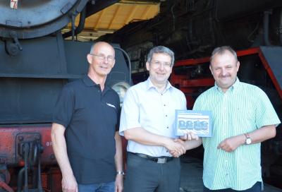 Frank Müller (li) und Dirk Endisch übergeben Bürgermeister Hermann ein Exemplar ihres neuen Bildbandes über Dampflokomotiven (Bild vergrößern)