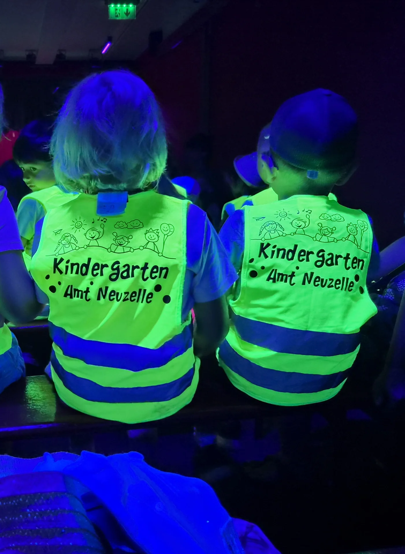 Kinder in Warnwesten schauen sich Puppenspiel an
