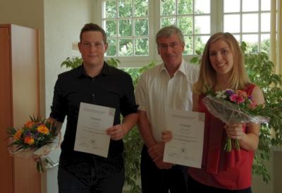 Bürgermeister Heiko Müller gratuliert den beiden Auszubildenden zum bestandenen Abschluss