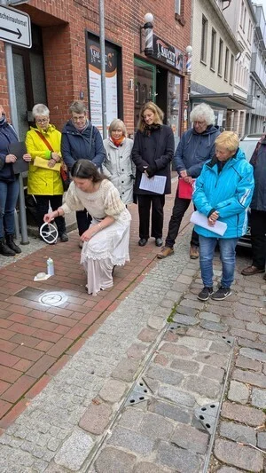 Künstlerin Nele Borchert lässt neben dem Stolperstein für die Familie Rosenberg in der Domstraße symbolisch ein Aufsprühbild mit Nadel und Faden entstehen, das an das traditionsreiche Textilkaufhaus der Familie erinnern soll. © Stadt Ratzeburg